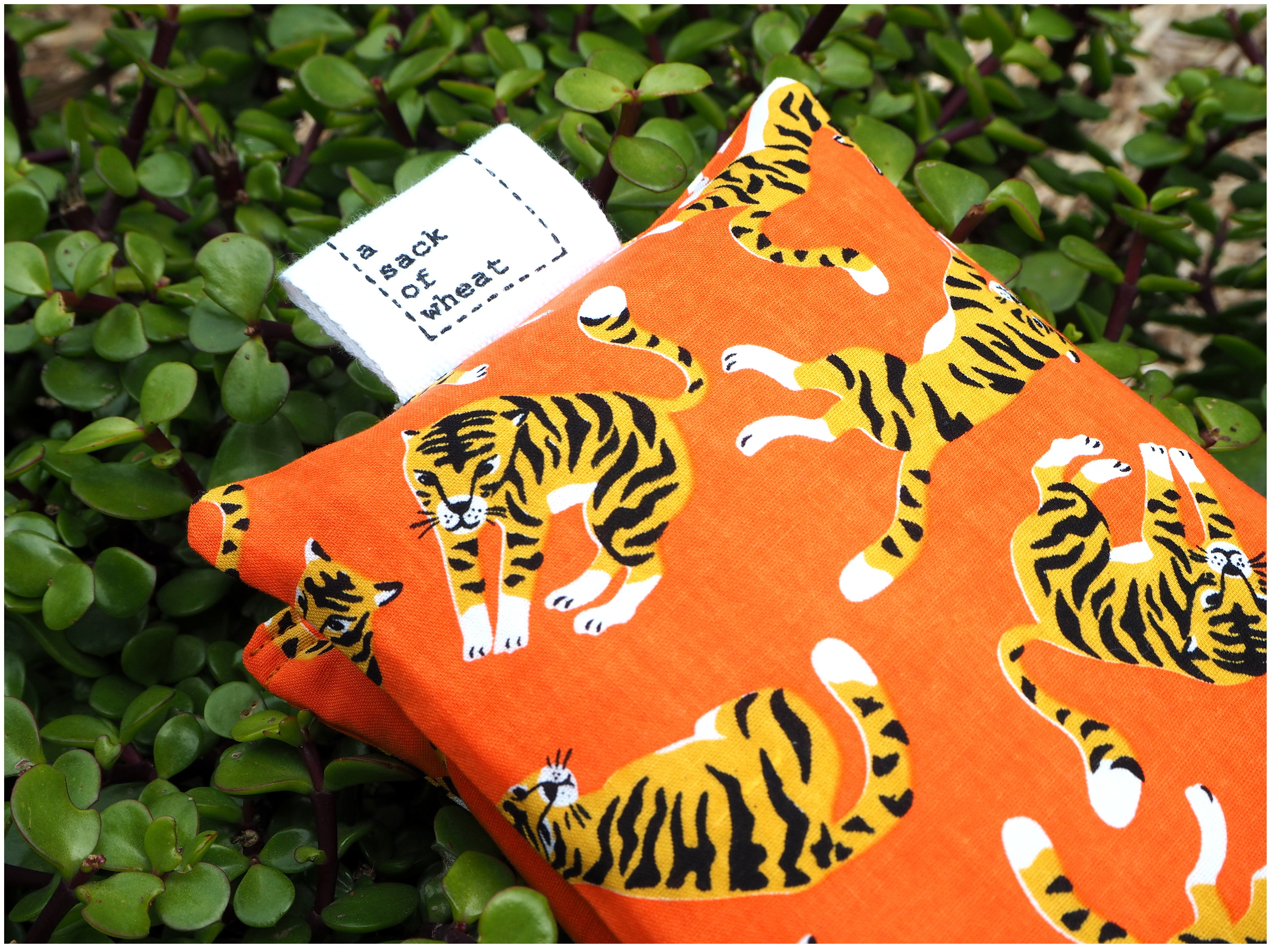 Folded view of A Sack Of Wheat, featuring  colorful tigers on bright orange fabric. 100% cotton fabric.