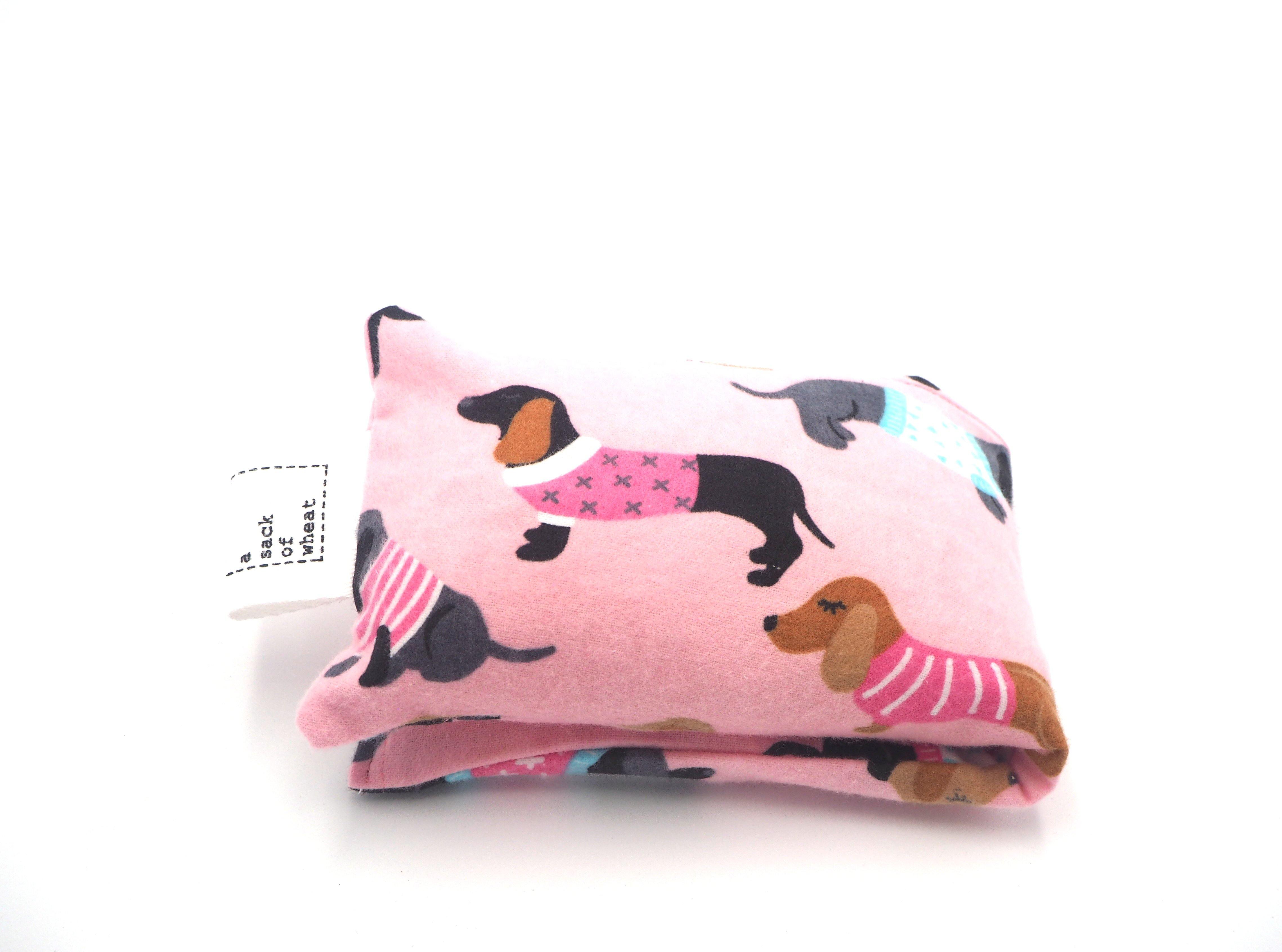 Folded view of A Sack Of Wheat, featuring dogs in cute jackets on soft pink flannelette 100% cotton fabric