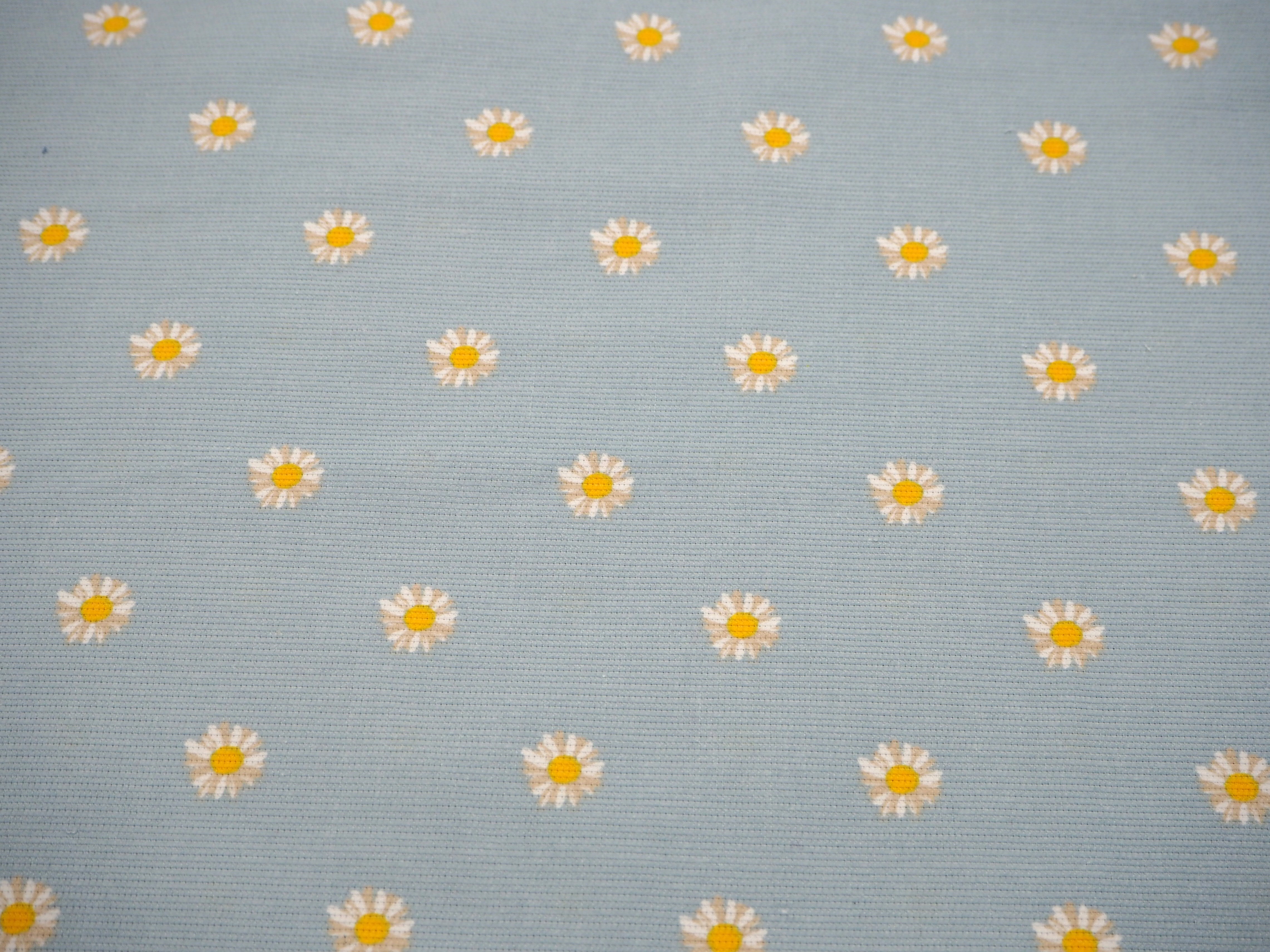 Fabric view of A Sack Of Wheat, featuring soft yellow, spring daisy's on baby blue corduroy 100% cotton fabric