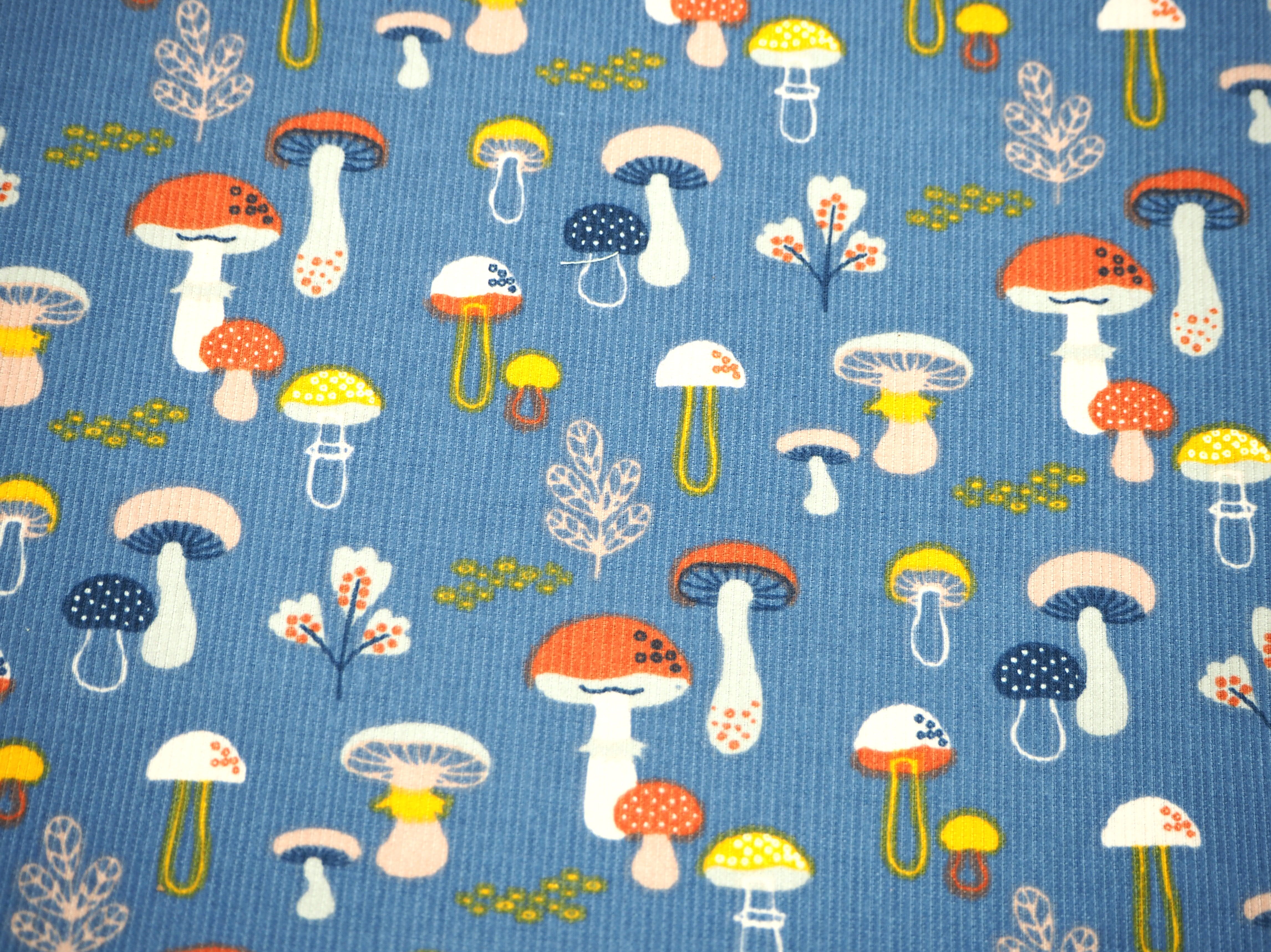 Fabric view of A Sack Of Wheat, featuring cute, colorful mushrooms on blue corduroy 100% cotton fabric