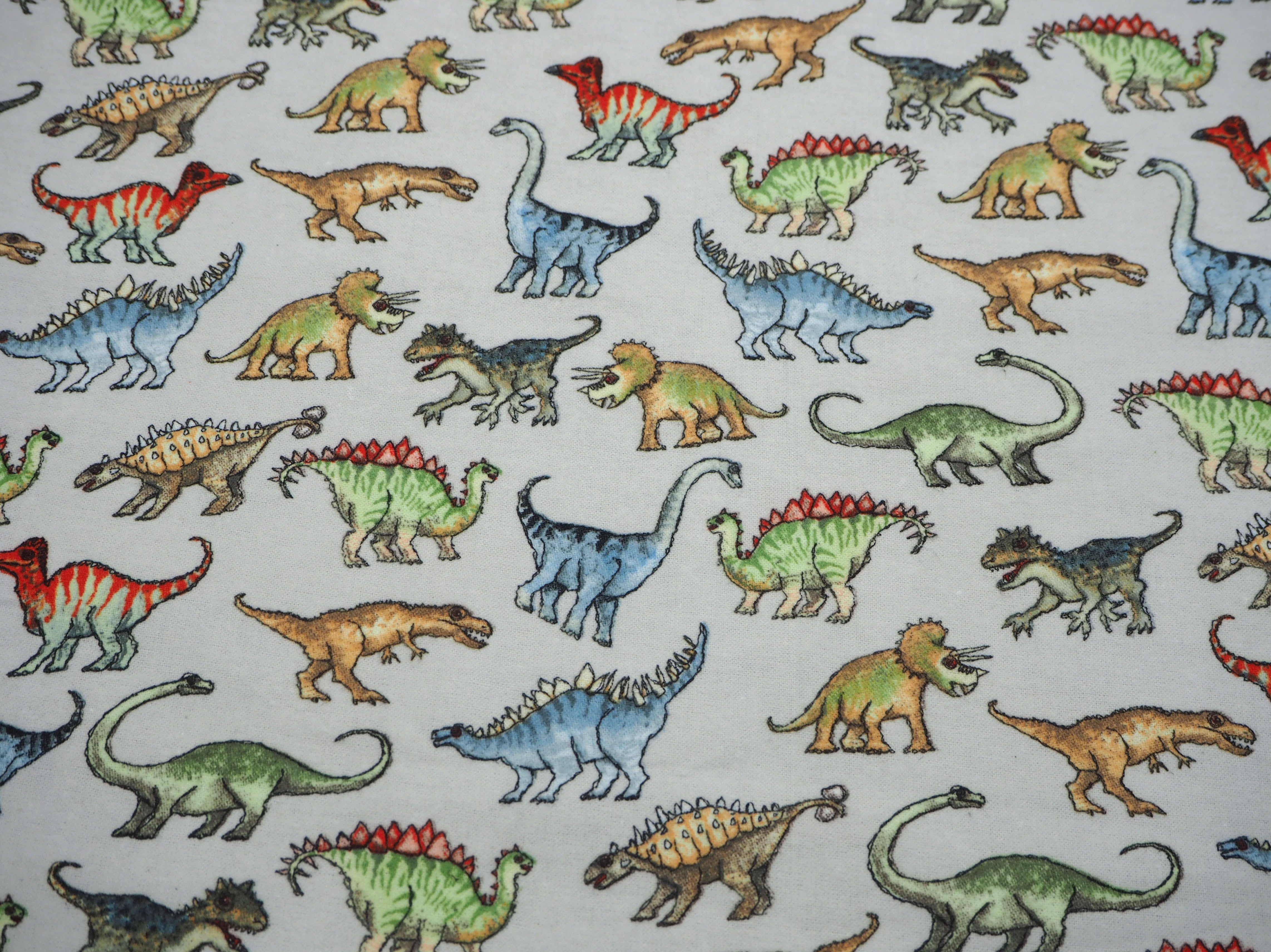 Flannelette fabric featuring colorful dinosaurs on soft grey background
