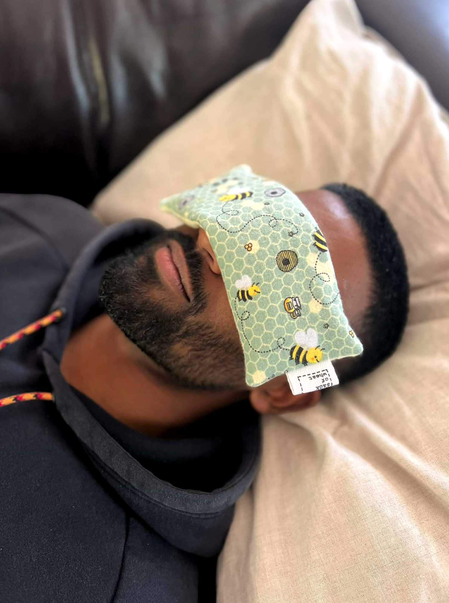 Person lying on a couch  with The Bee eye pillow on forehead relaxing.