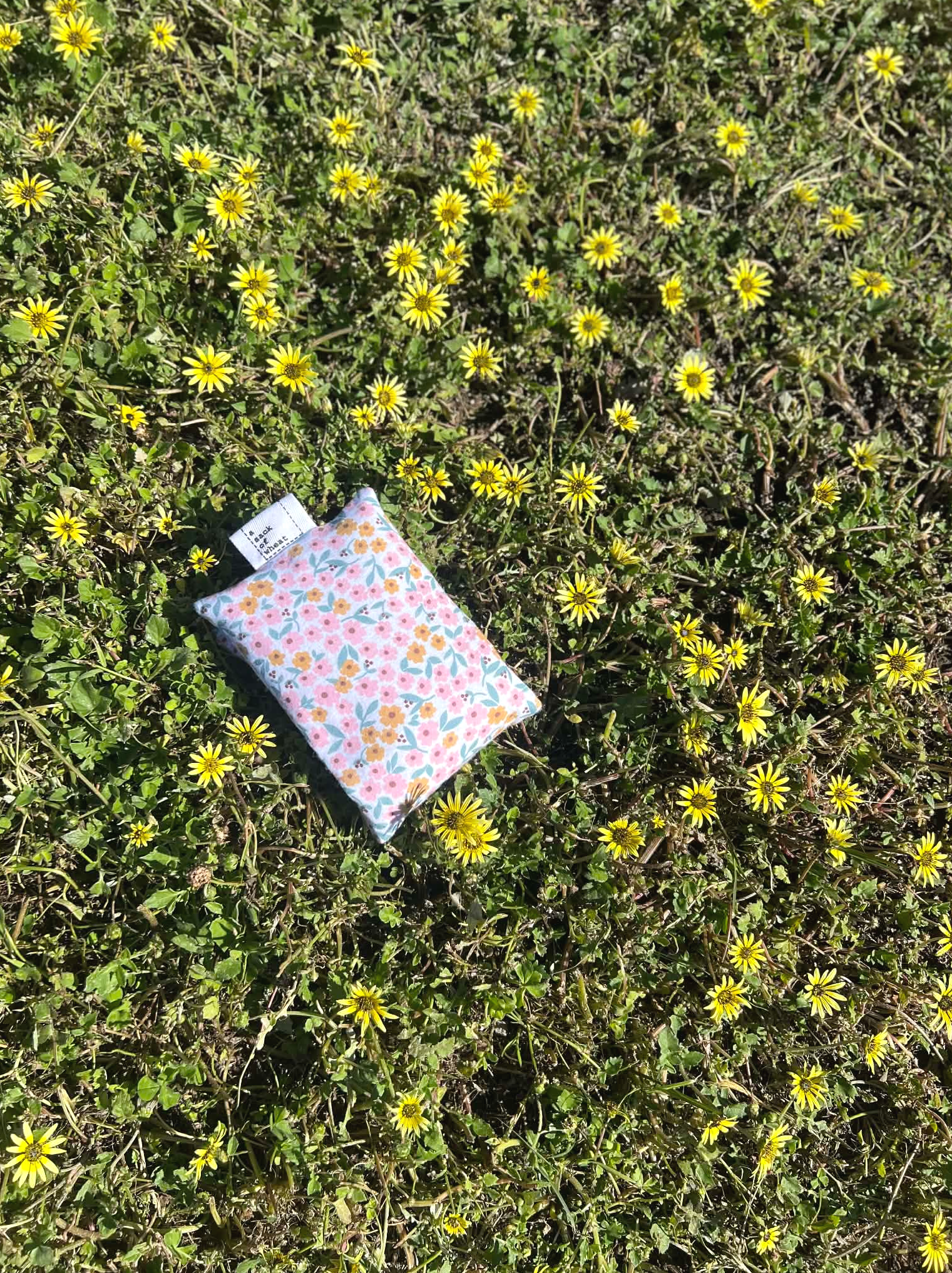 Floral-patterned fabric on a grassy area with yellow flowers