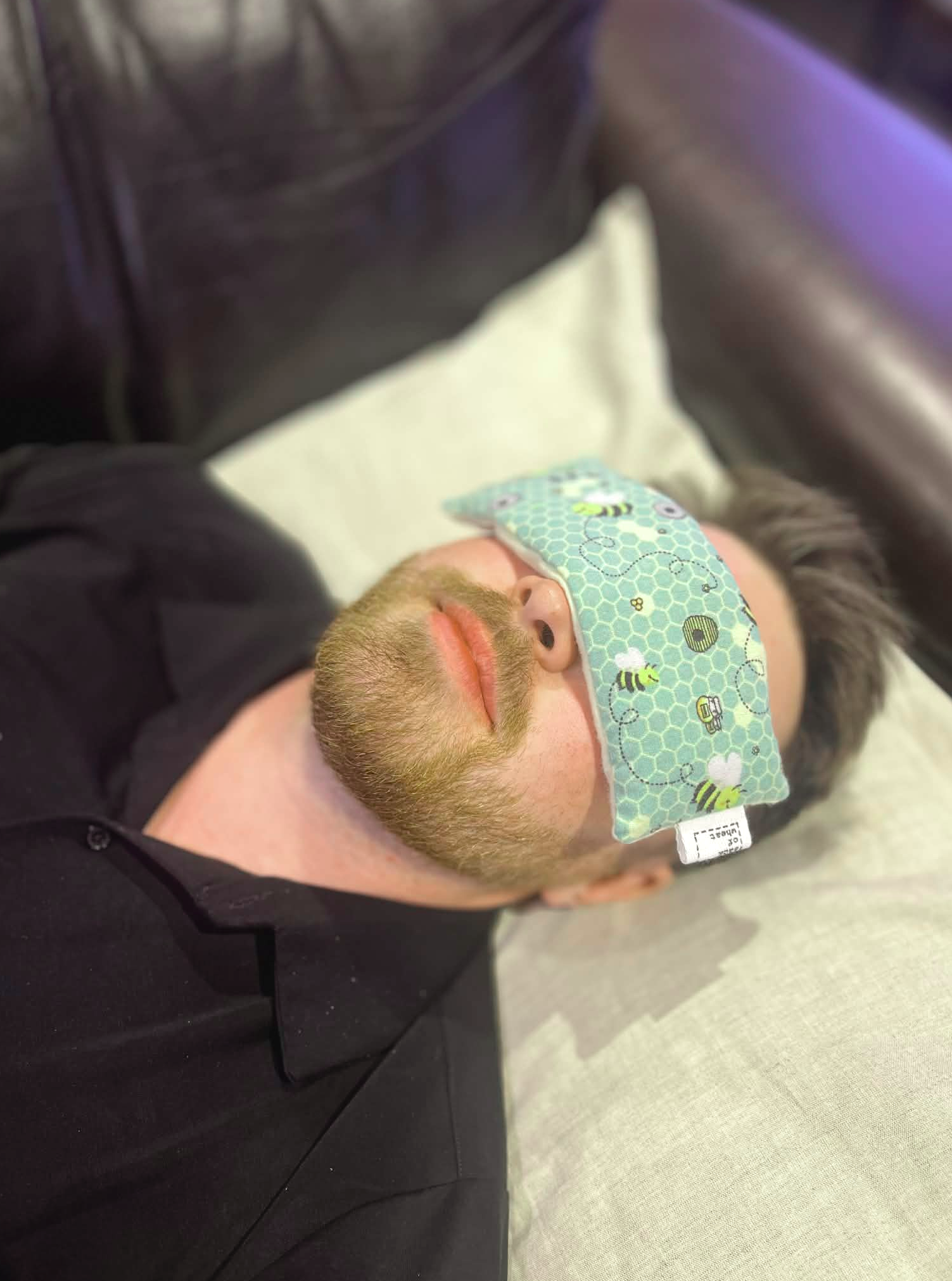Person wearing The Bee eye pillow  sitting on a couch